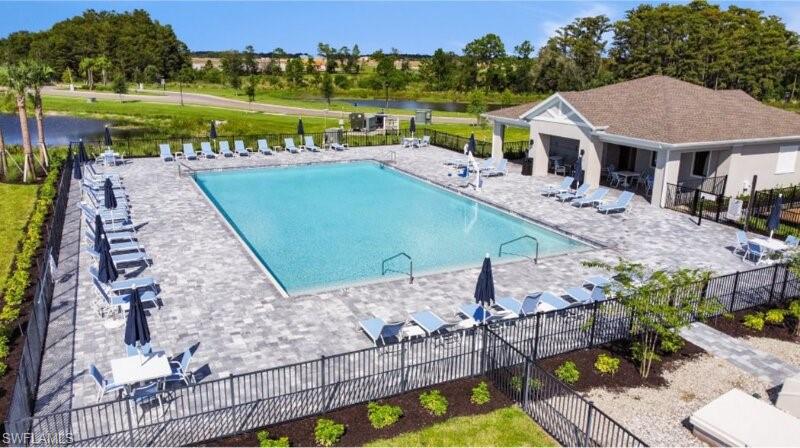 Community swimming pool with surrounding paver deck, lounge seating, and a covered clubhouse