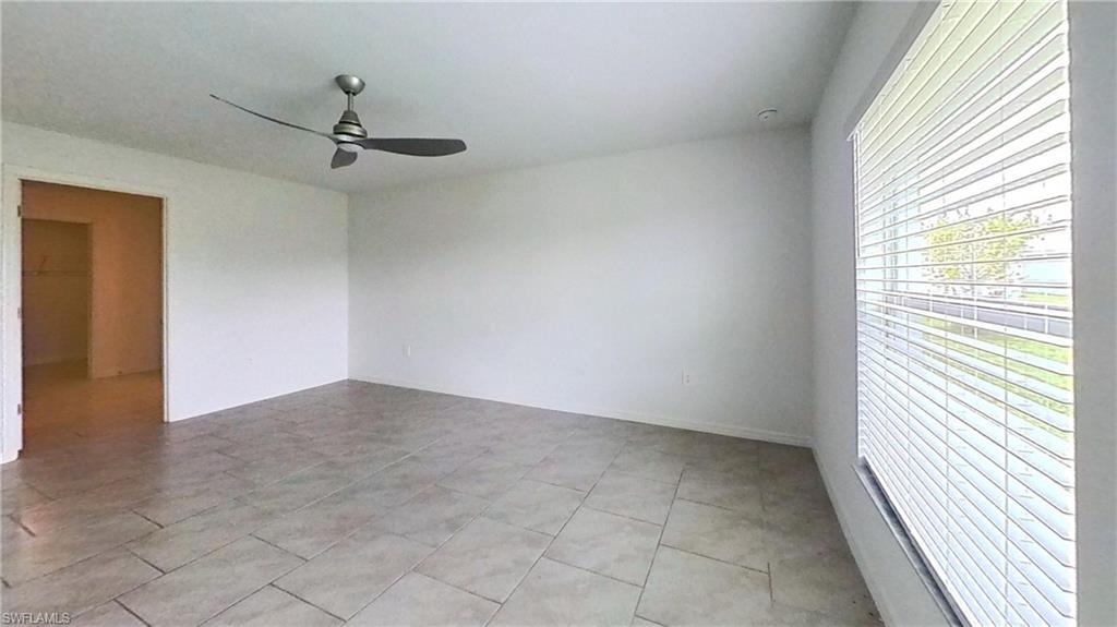 Spacious room with large format tile flooring, a contemporary ceiling fan, and a wide window with horizontal blinds