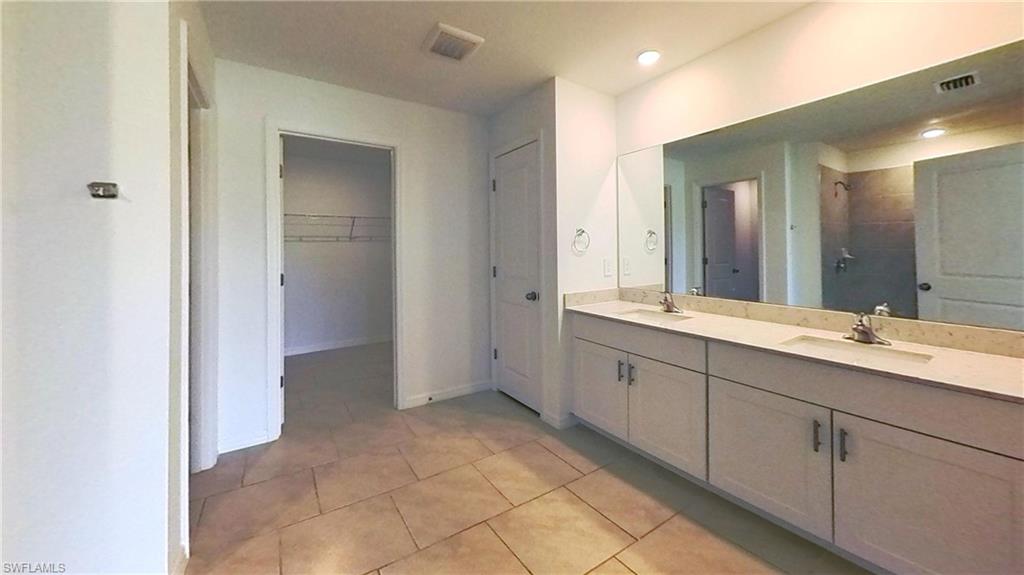 Spacious bathroom featuring a dual vanity with light countertops and white cabinetry