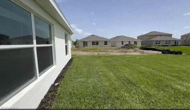 Expansive green space with an exterior wall featuring large windows and white trim