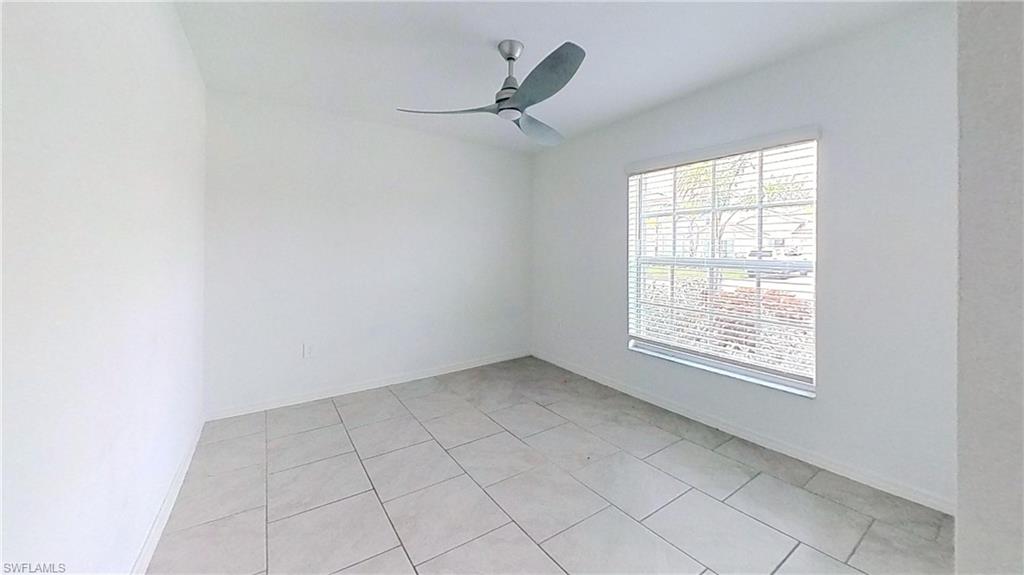 Neutral wall finishes, a modern ceiling fan, and tile flooring define this bright room