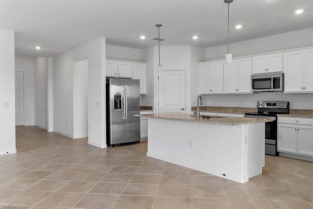 Kitchen featuring white cabinetry, granite countertops, stainless steel appliances, a central island with pendant lighting, and tiled flooring