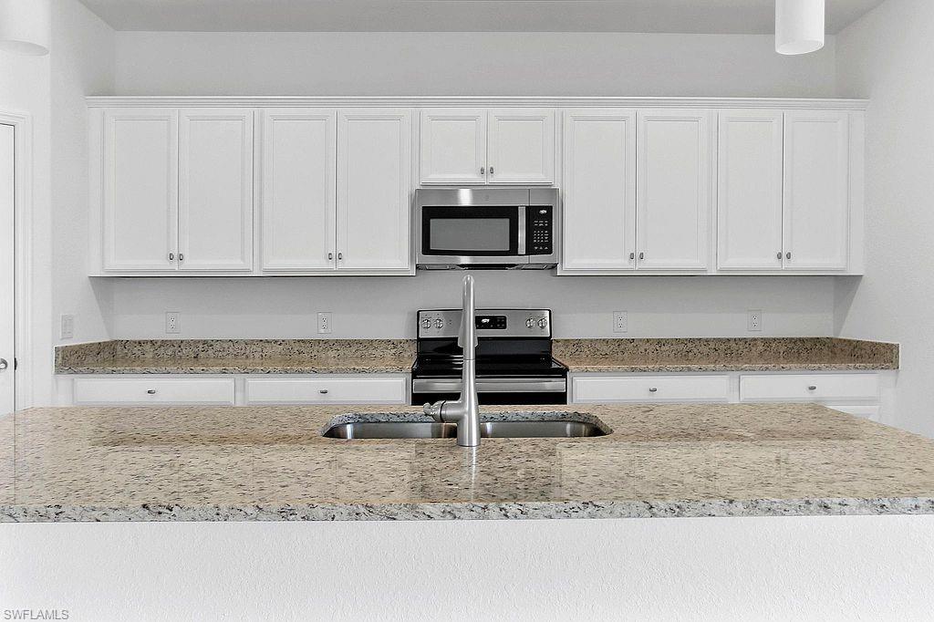 Kitchen featuring white shaker-style cabinetry, a stainless steel microwave, and a range with coordinating stainless steel appliances