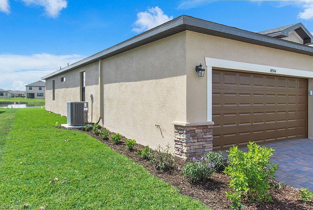 Neutral-toned stucco exterior with a brown paneled garage door and stone-accented column