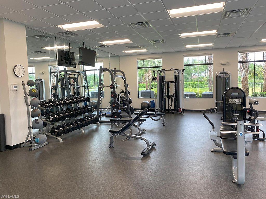 Fitness center featuring extensive mirrored walls, rubber flooring, and multiple large windows