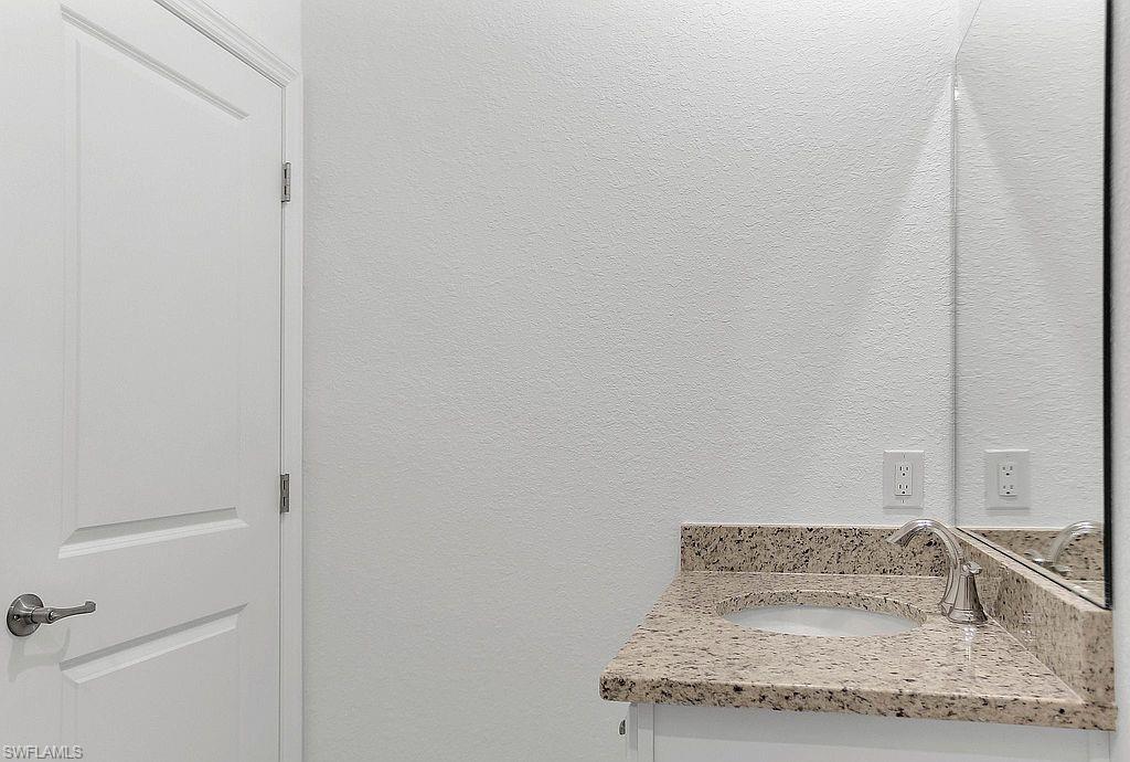 Bathroom vanity featuring a speckled countertop, integrated sink, and polished chrome faucet