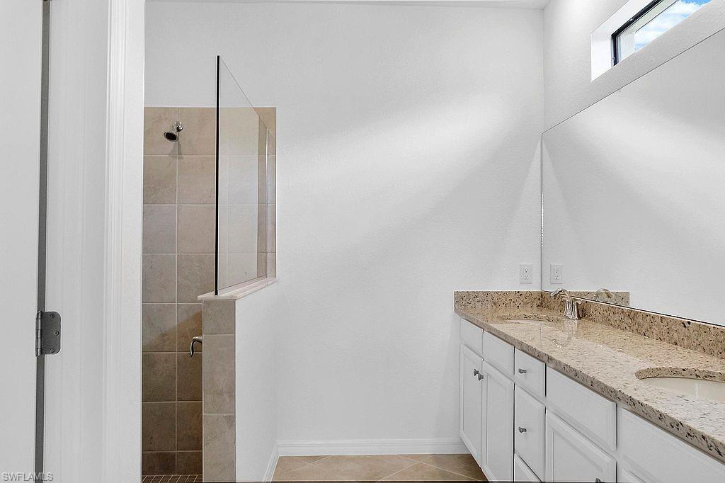 Bathroom featuring a dual vanity with light-toned countertop, integrated sinks, and polished chrome fixtures