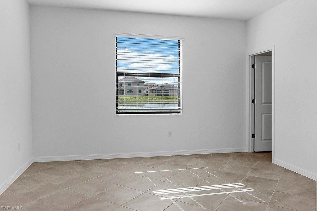 Room with neutral wall paint, tile flooring, a window with horizontal blinds, and a paneled interior door