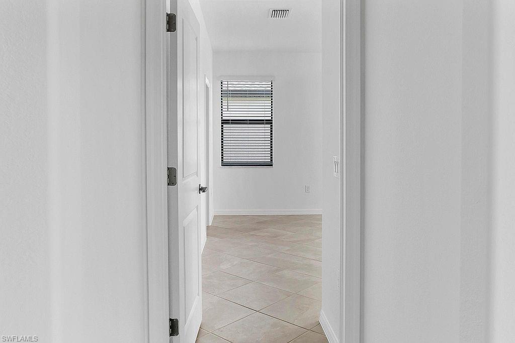 Room featuring neutral wall tones, square tile flooring, and a single window with horizontal blinds