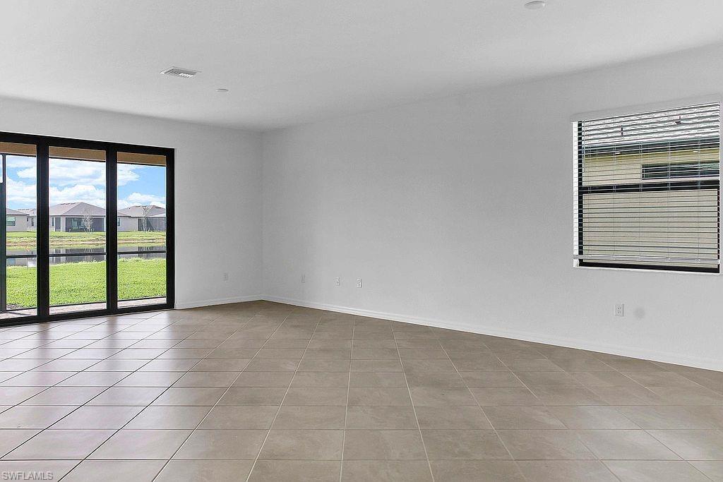 Spacious room with large format floor tiles, white walls, and a recessed ceiling light