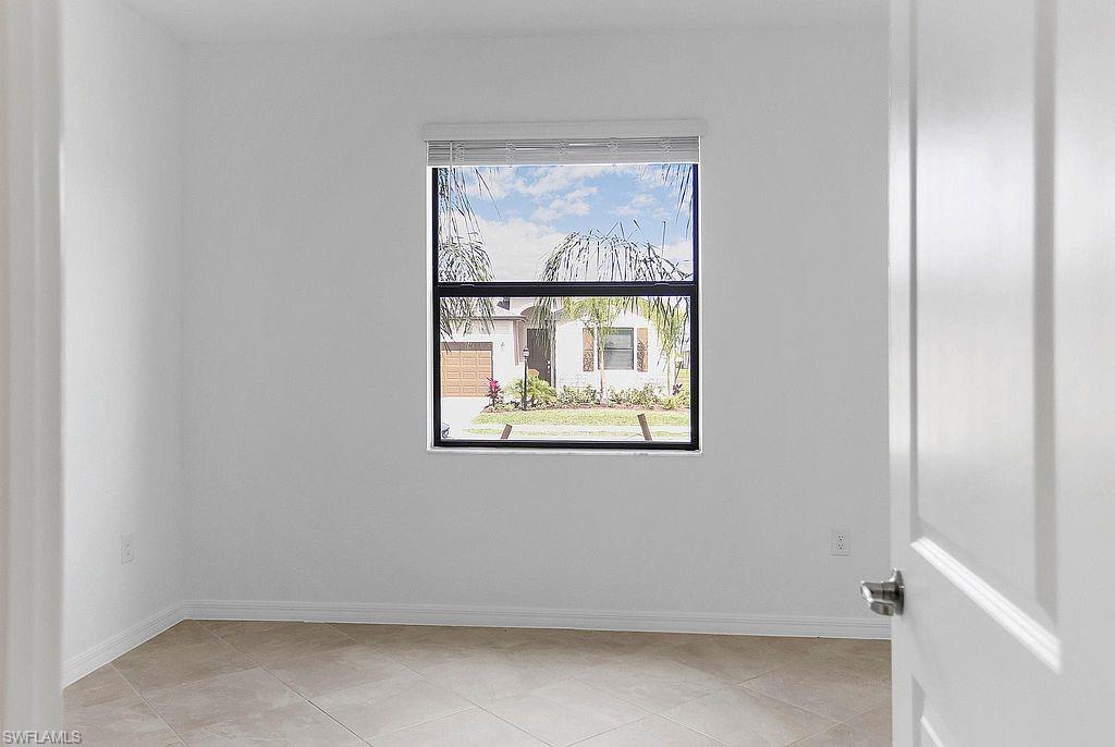 Room featuring neutral wall tones, square tile flooring, white baseboards, and a single window with white blinds