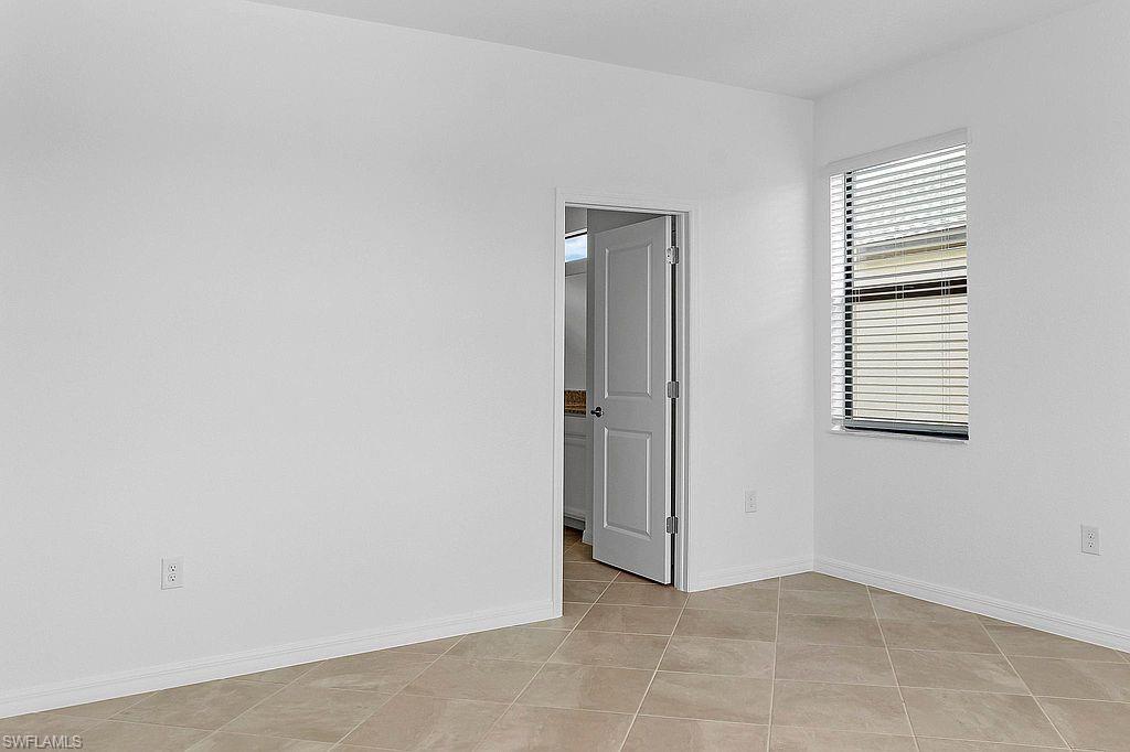 Room featuring neutral tile flooring, white baseboards, and a doorway leading to an interior space