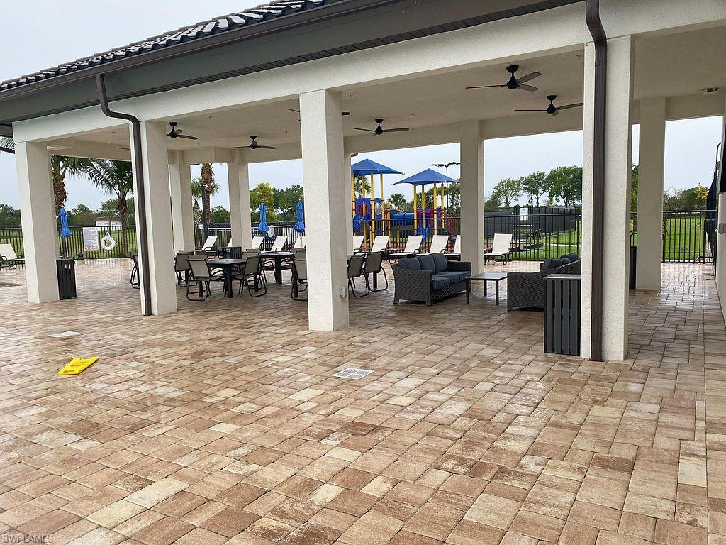 Expansive covered patio featuring a paver flooring, multiple ceiling fans, and structural columns