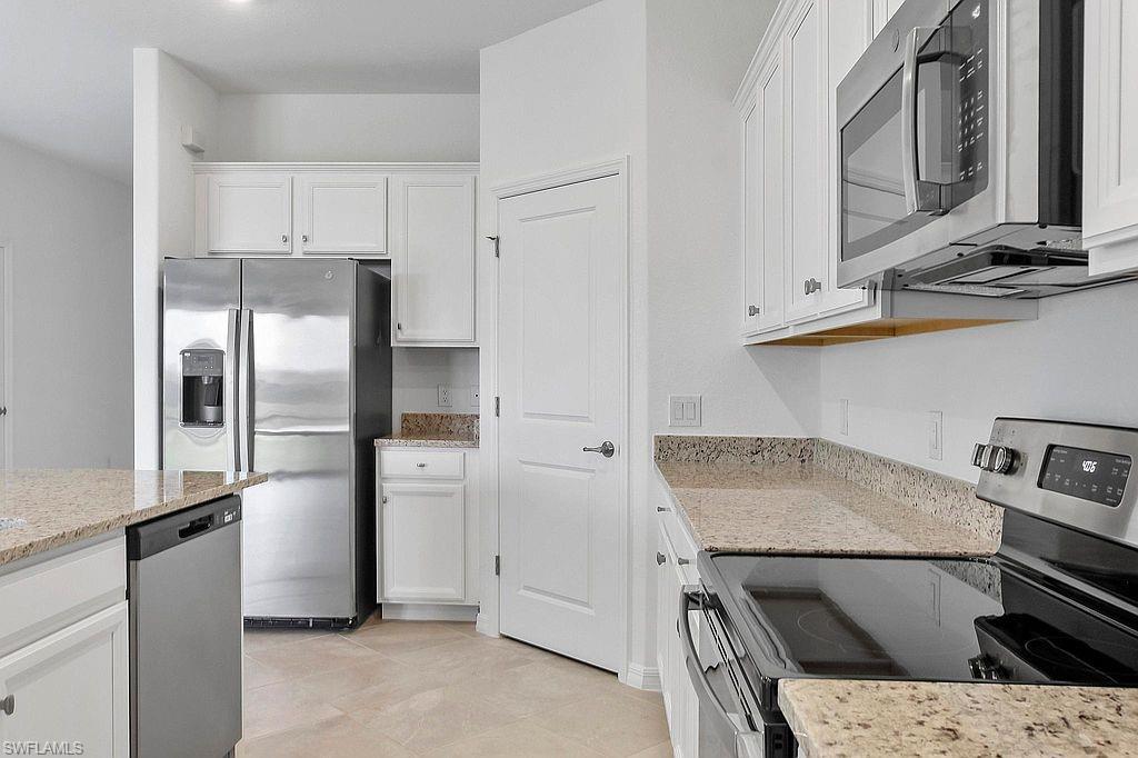 Kitchen featuring stainless steel appliances, white cabinetry, granite countertops, and tile flooring
