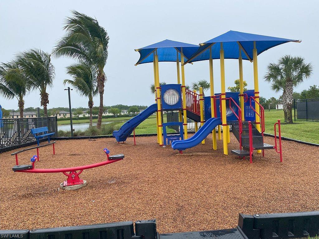 Community playground featuring a multi-level play structure with slides and shade canopies