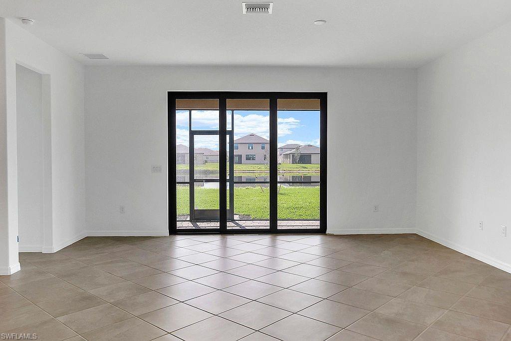 Tiled flooring throughout this open space, featuring a large black-framed sliding glass door with screens
