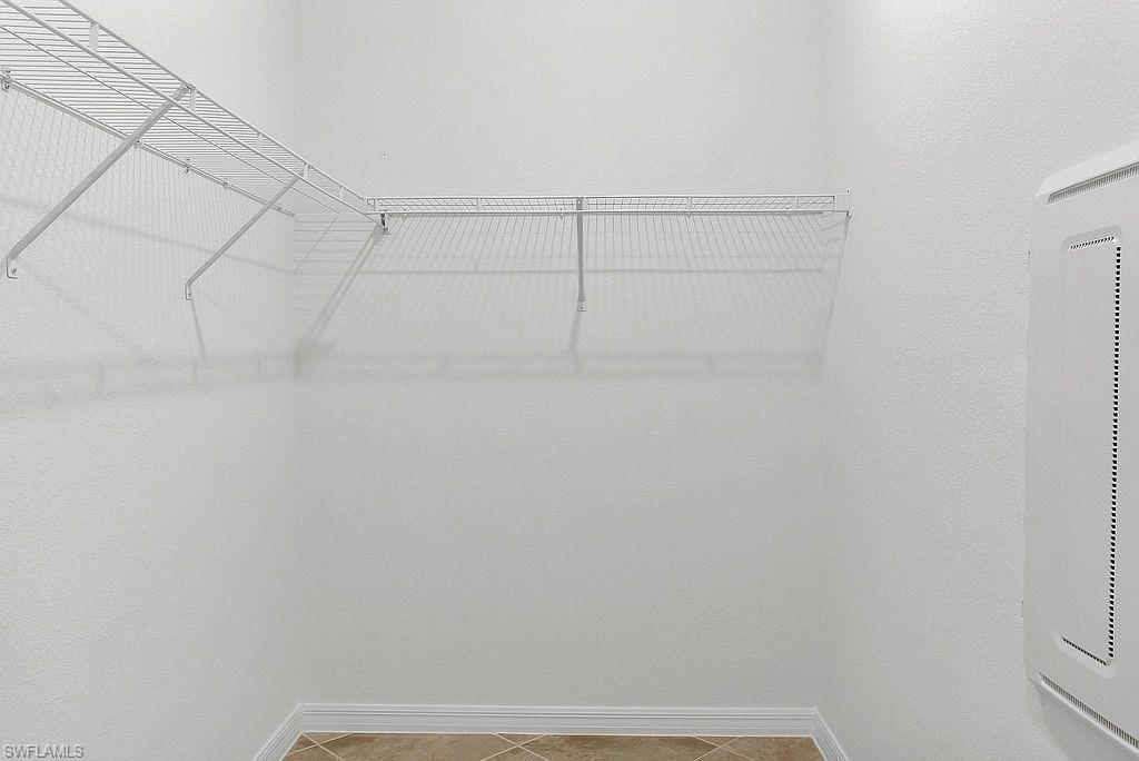 White wire shelving system in a walk-in closet with neutral-toned floor tile and white baseboards