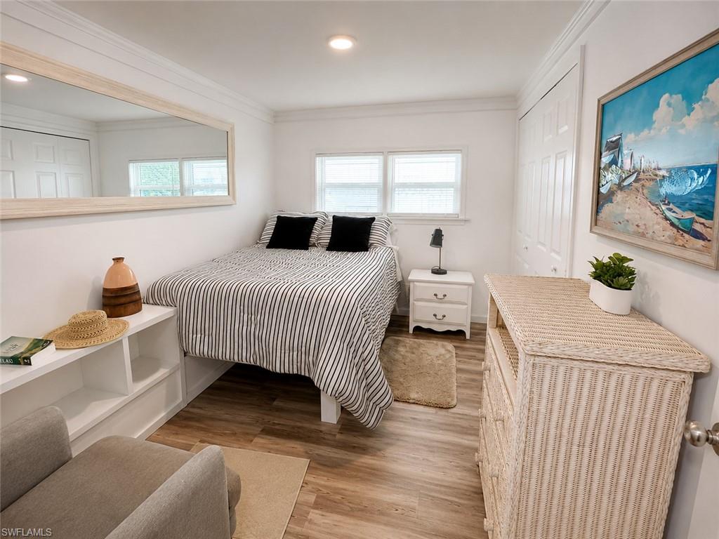 Wood-finish flooring, white walls, and crown molding