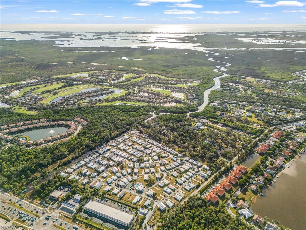 Expansive aerial of a residential community featuring a golf course, a winding river, and a large body of water