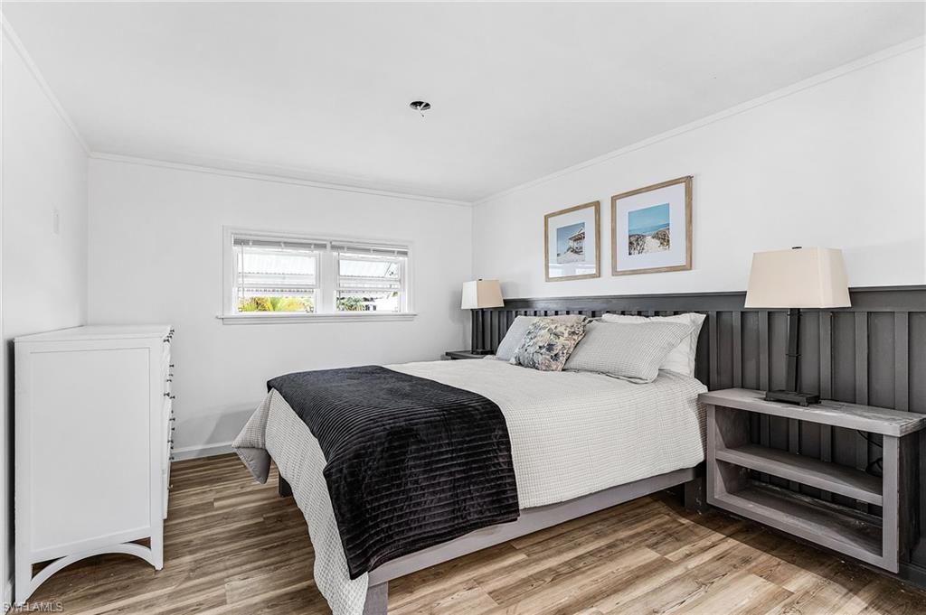 Bedroom featuring wood-finish flooring, white walls, and crown molding