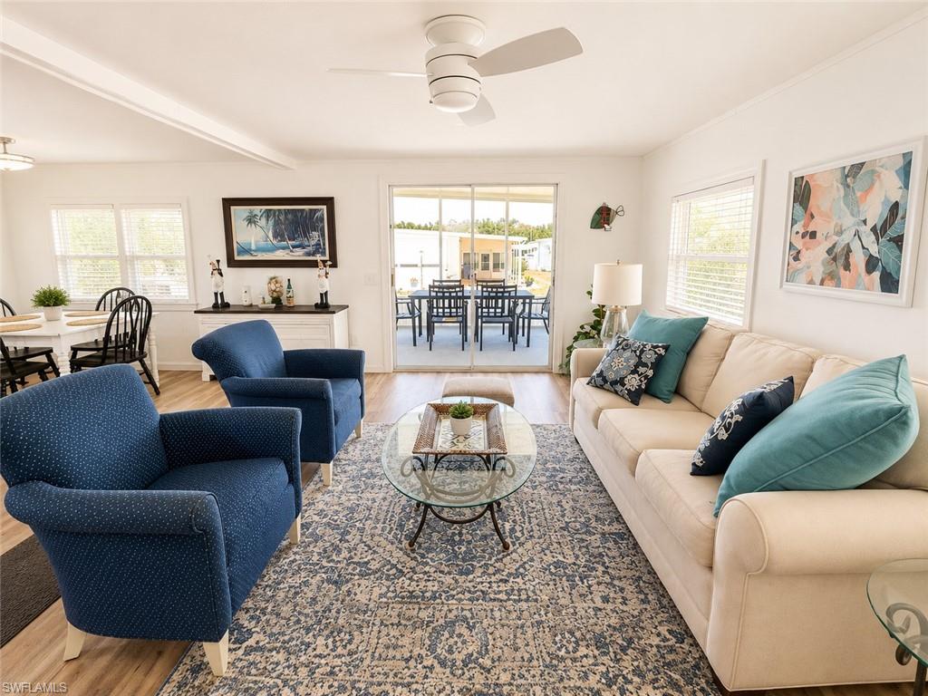 Open-concept living area with wood-finish flooring, a white ceiling fan, and sliding glass doors opening to an outdoor patio