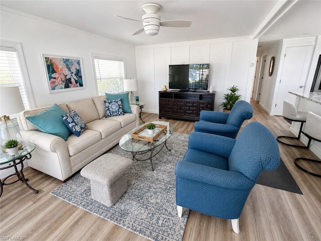 Living area with wood-finish flooring, white panel wall, and ceiling fan