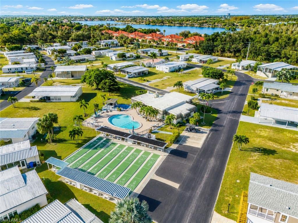 Community featuring a large swimming pool, shuffleboard courts, and mature landscaping