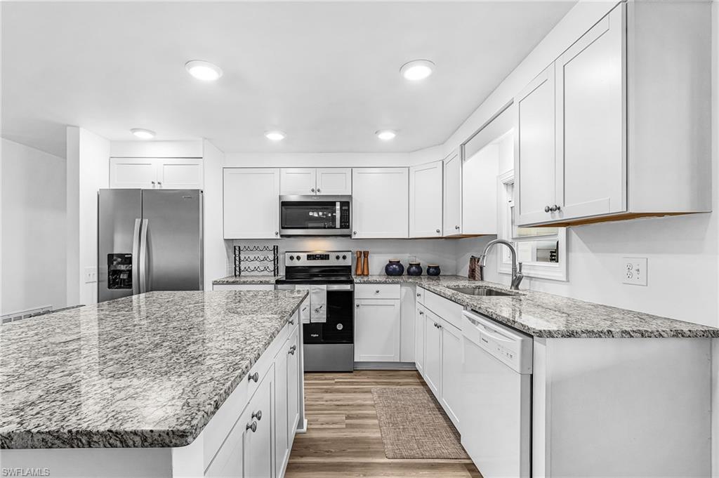 Wood-finish flooring, recessed ceiling lighting, a contemporary flush-mount light fixture, and multiple windows with blinds
