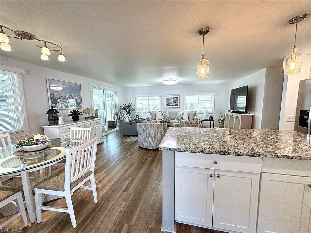 Spacious living area featuring wood-finish flooring, a modern ceiling light fixture, and multiple windows