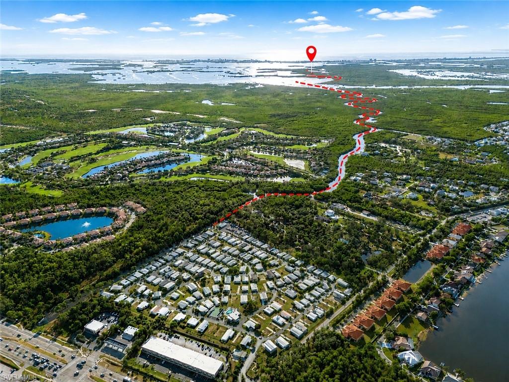Aerial perspective showcasing residential developments, extensive green spaces, and a prominent body of water with a distinct shoreline