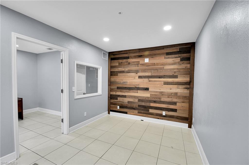 Accent wall featuring varied wood-finish planks, recessed ceiling lighting, and light tile flooring