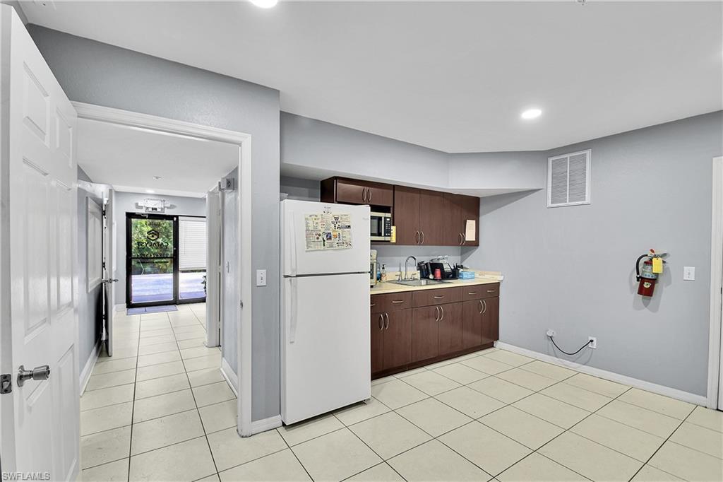 Kitchenette featuring wood-finish cabinetry, a stainless steel sink, and light-toned countertops