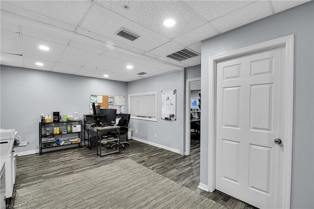 Spacious room featuring wood-finish flooring, light grey painted walls, and a white six-panel door