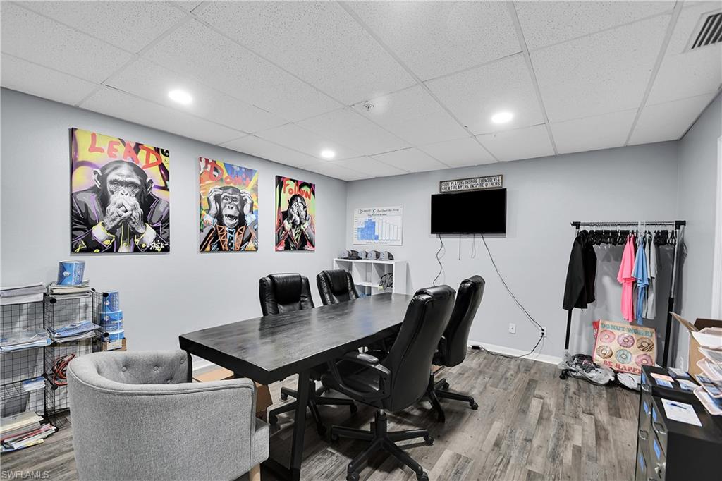 Spacious room featuring wood-finish flooring, light grey walls, and a drop ceiling with recessed lighting
