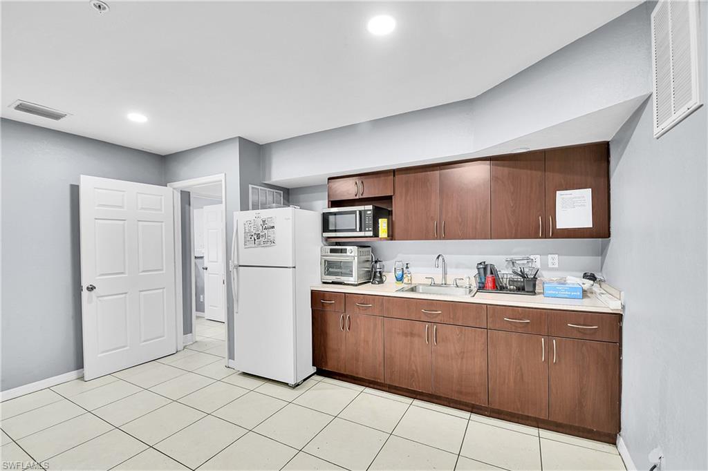 Kitchenette featuring wood-finish cabinetry, light-toned countertops, and recessed lighting