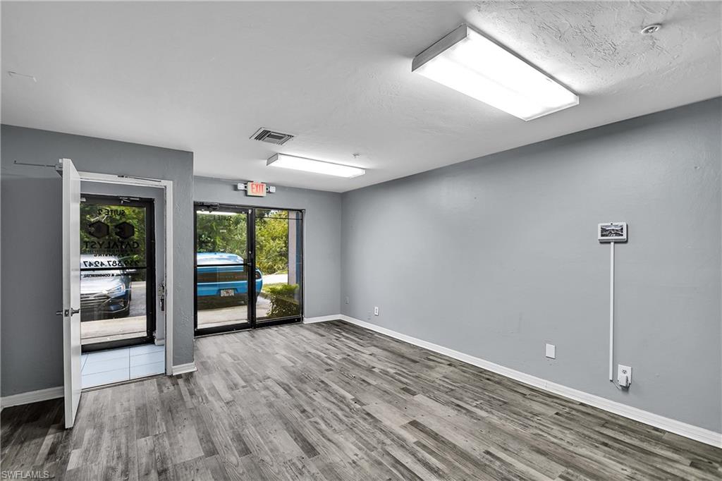 Spacious interior featuring wood-finish flooring, light gray walls, and bright overhead lighting