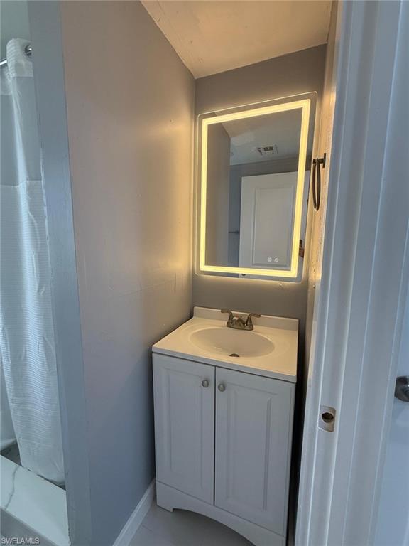 White vanity with integrated sink, brushed nickel faucet, and illuminated mirror
