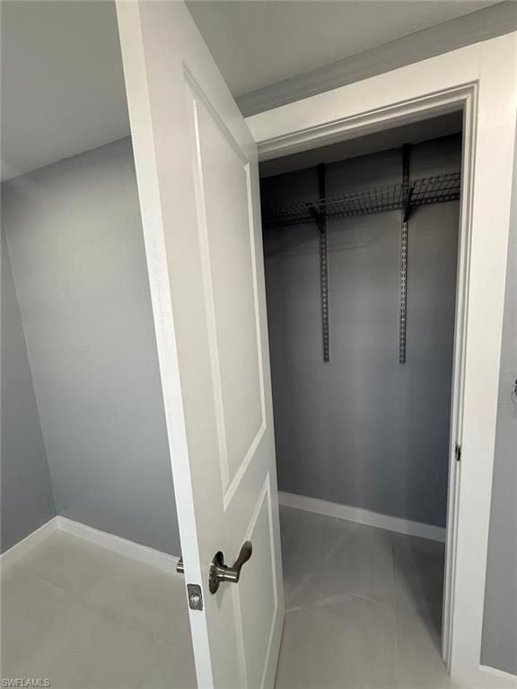 Interior closet featuring wire shelving, white trim, and a paneled door with brushed nickel hardware