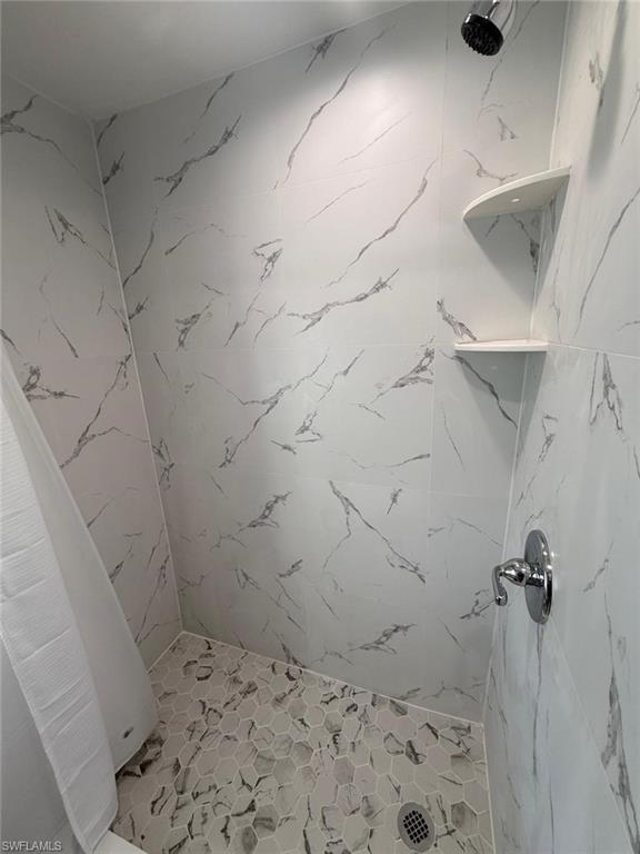 Tiled shower with white and grey marbled-pattern walls