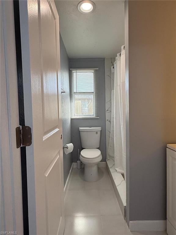 Bathroom with recessed ceiling lighting, a window featuring horizontal blinds, and a white toilet