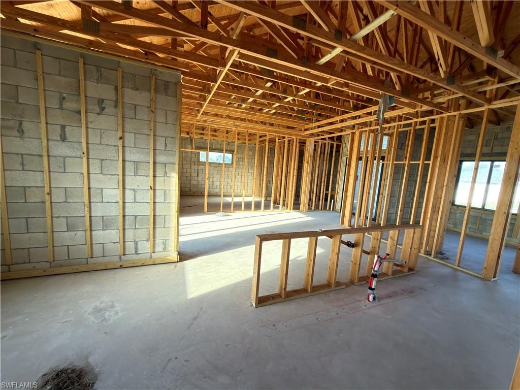 Framed interior construction featuring exposed wooden trusses, concrete block walls, and multiple window openings