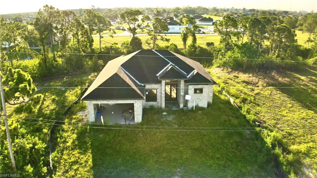 Newly constructed residence featuring a dark shingle roof, block exterior, and an integrated covered entry