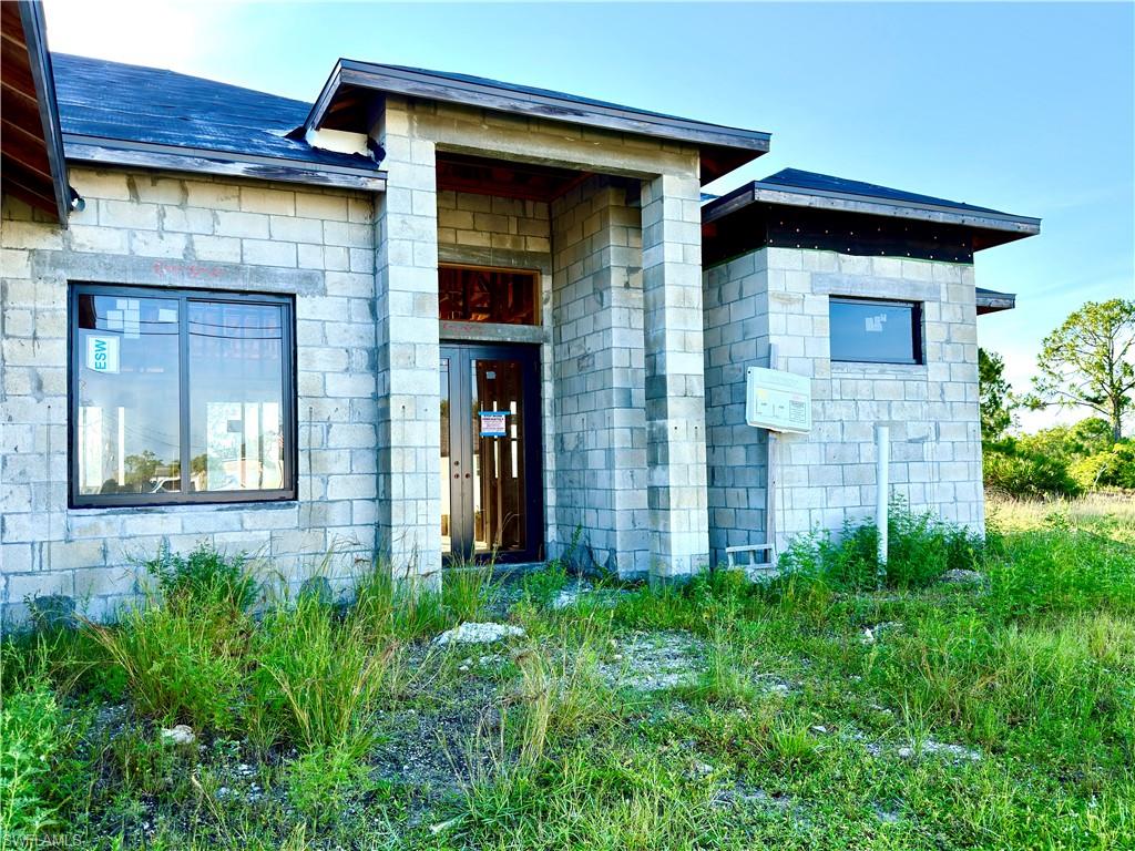 Modern concrete block construction featuring a dark shingle roof and a prominent double-door entry