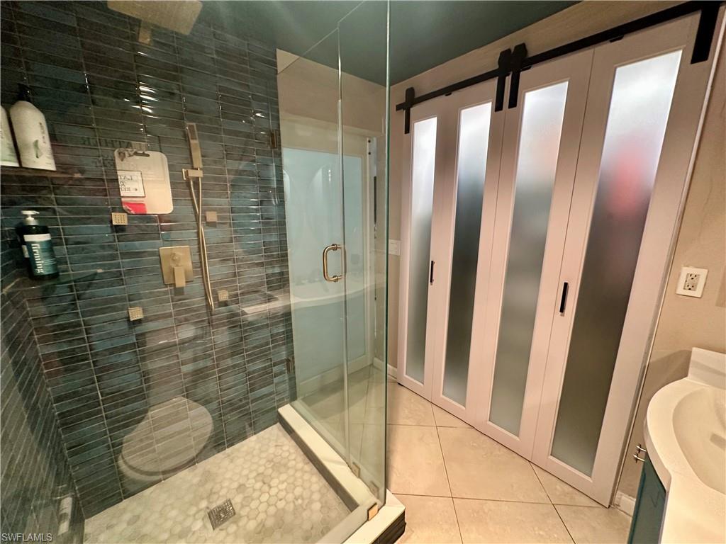 Shower with dark blue subway tile, a brass-finish shower system, and a white hexagonal tile floor