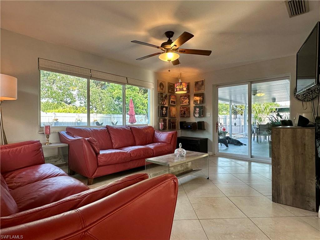 Spacious living area featuring large windows with natural light, tiled flooring, and a ceiling fan with integrated lighting