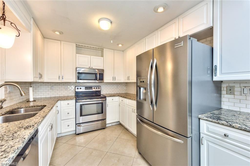 Kitchen featuring white shaker-style cabinetry, granite countertops, subway tile backsplash, stainless steel appliances, and tile flooring