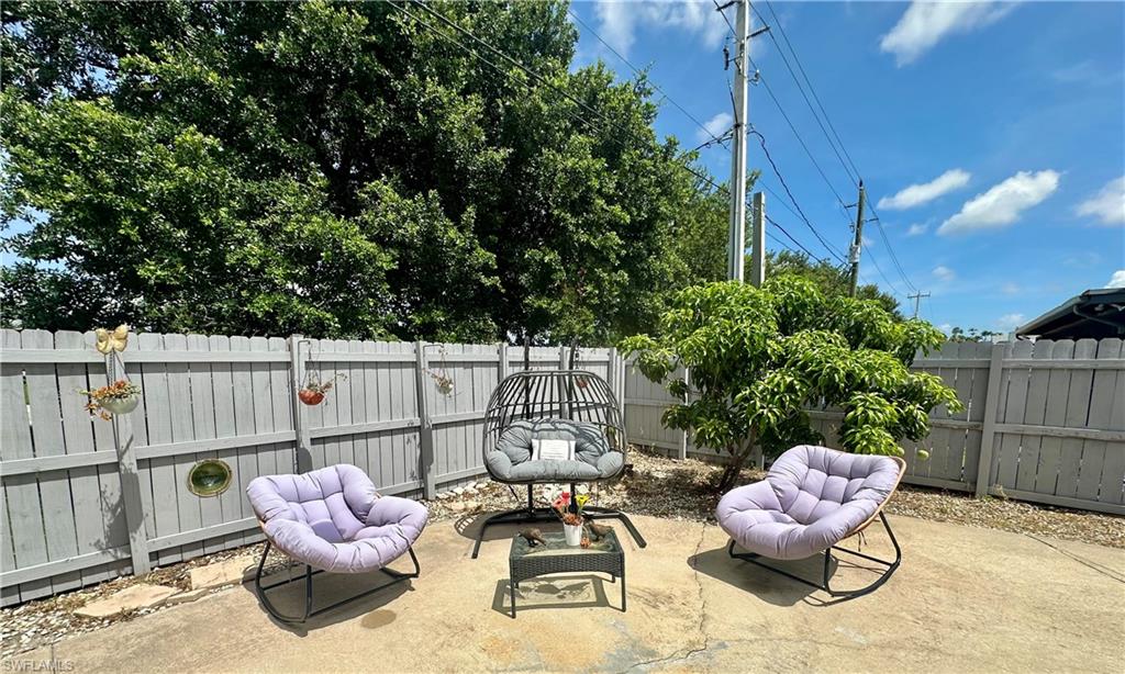 Paved patio area featuring a privacy fence, mature trees, and landscaping
