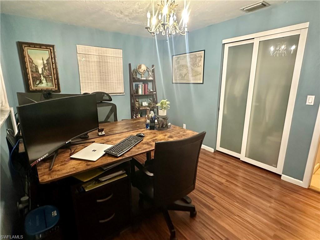 Interior room featuring wood-finish flooring, a decorative chandelier light fixture, and light blue wall tones