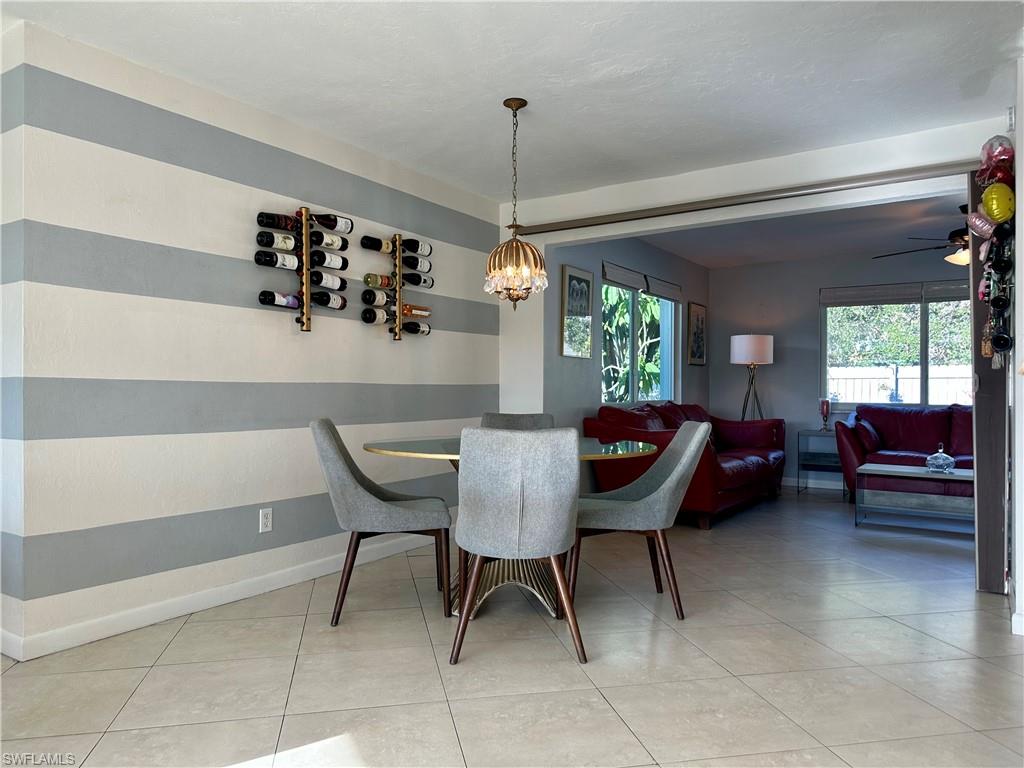 Open-concept living space featuring ceramic tile flooring, a decorative wall-mounted wine rack, and a cased opening to the room beyond