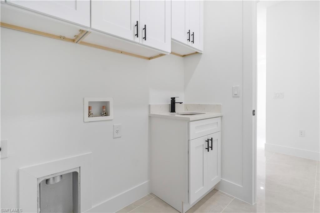 Laundry space featuring white shaker cabinetry with matte black hardware, a light-colored countertop, and a built-in sink with a matte black faucet